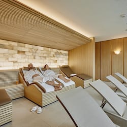 Relax in a serene spa room with a massage table, reclining chairs, and wall-mounted massage area.