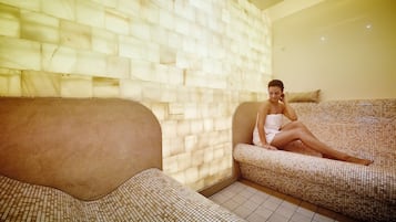 Un cuarto de spa con piso de baldosas, un banco acolchado y una pared con textura.