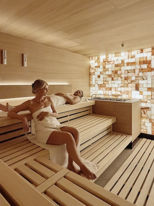 Relax in a serene spa room with a minimalist design, featuring two benches and a small table.