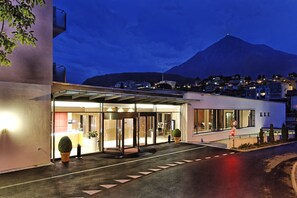 Ein Hotel Eingang mit Glastür, einer Drehschranke und einem Blick auf einen Berg im Hintergrund.