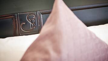 A bed with a pillow and a headboard with a monogram.
