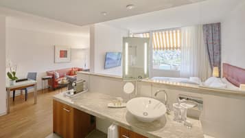 Un baño moderno con un lavamanos grande, un espejo y una ducha. Hay una zona de comedor con una mesa y sillas, y un sofá.