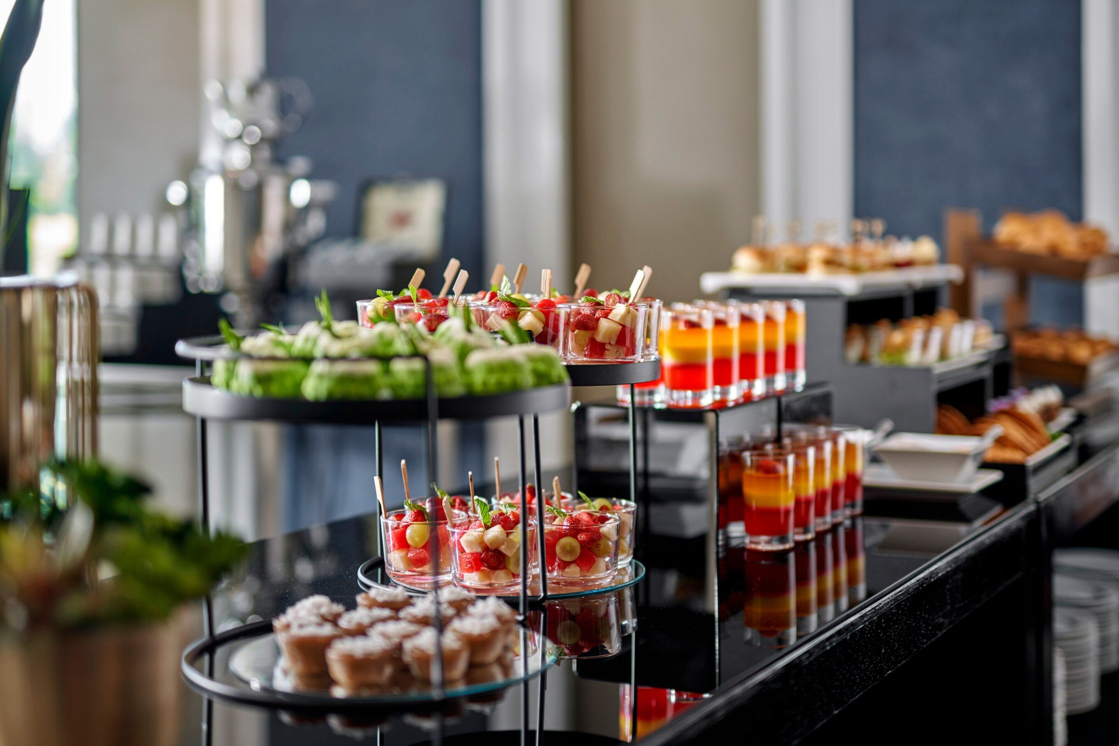 Un buffet proposant une variété de plats, notamment des brochettes de fruits, des pâtisseries et des boissons.