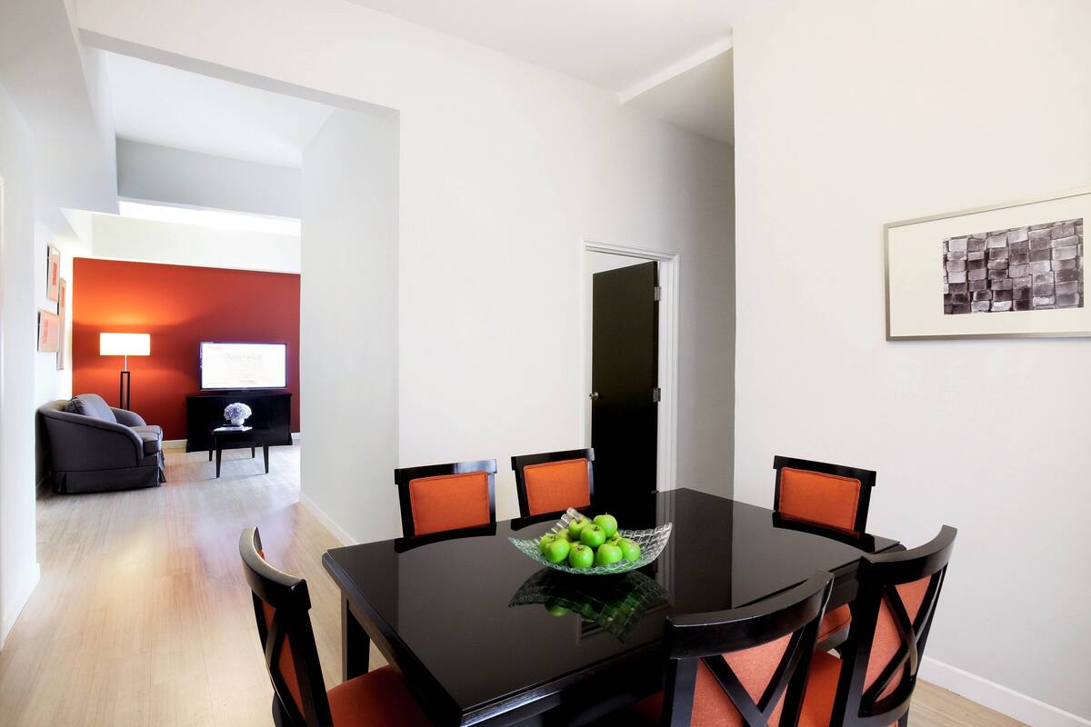 A dining area with a black table, four chairs, and a bowl of green apples.