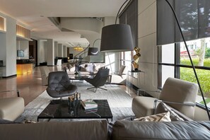 A spacious living area with modern furniture, a large window offering a view of greenery, and a sleek, contemporary design. - AC Hotel by Marriott Penang (George Town)