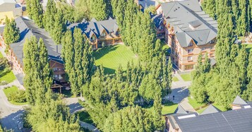 Vista aérea de una cabaña con varias edificaciones, rodeada de bosque denso.