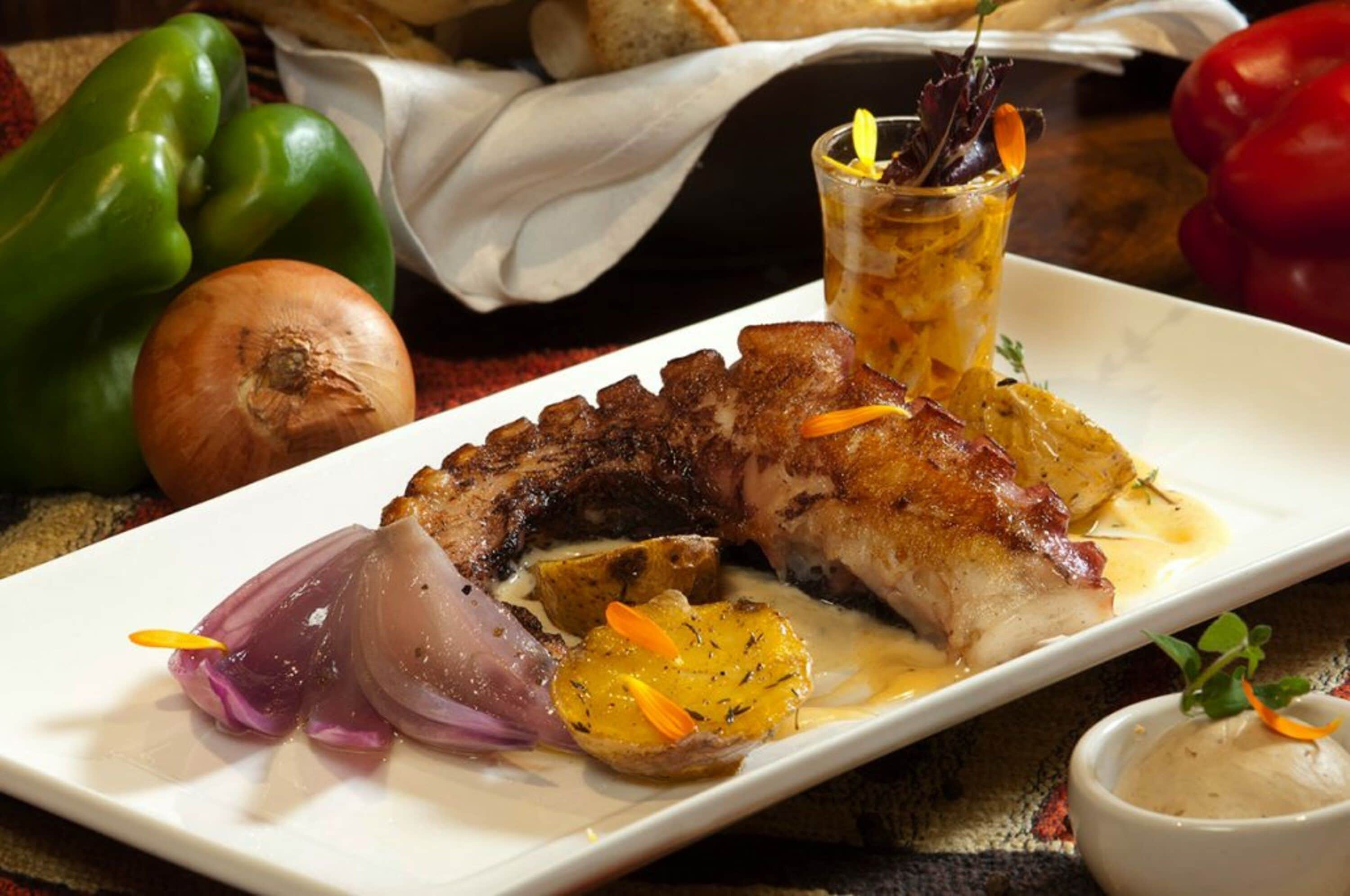 A plate of food with a piece of meat, vegetables, and a drink.