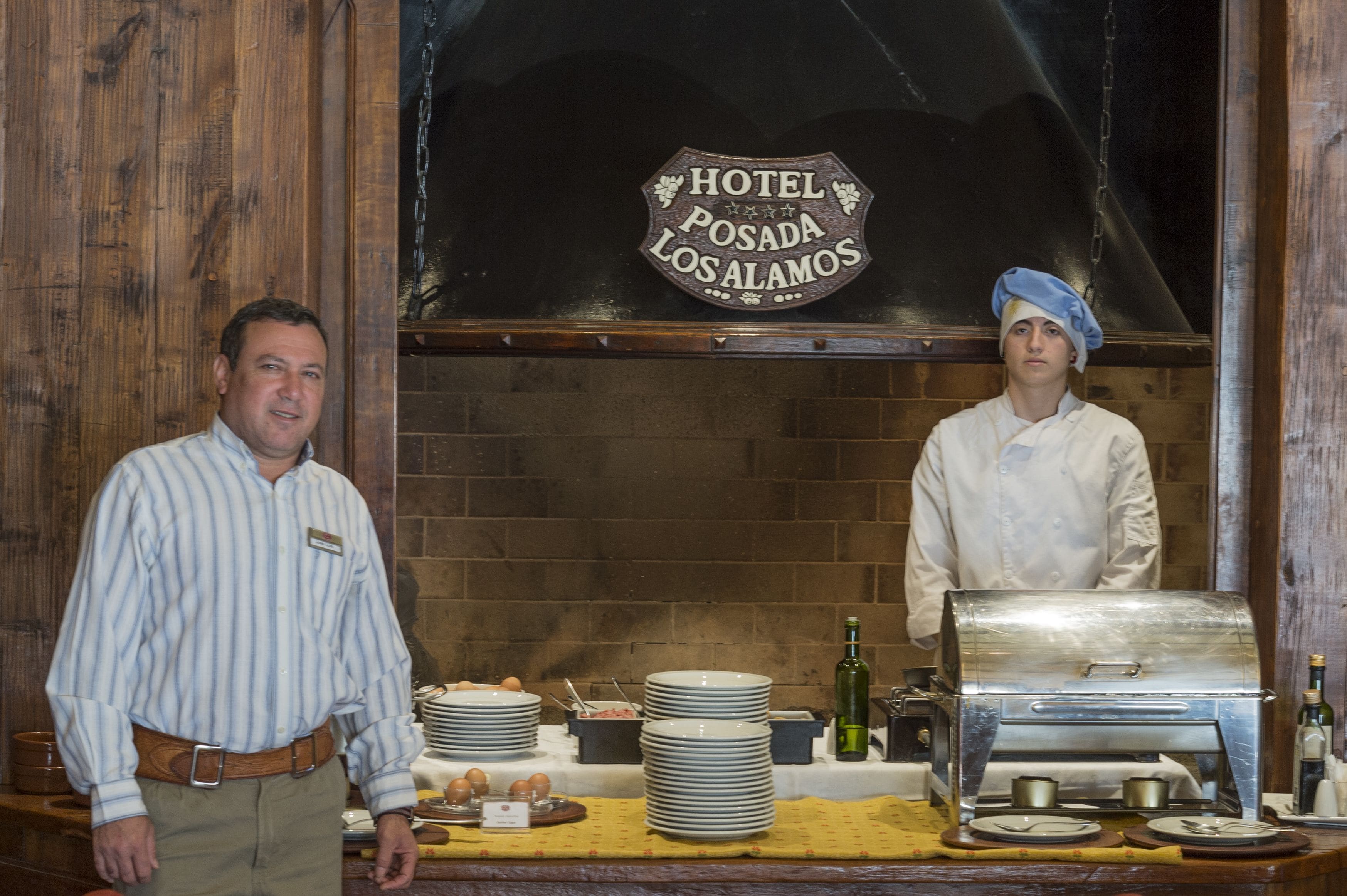 Una cocina de hotel con una parrilla, platos y un letrero que dice "Hotel Posada Los Alamitos".