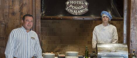Una cocina de hotel con una parrilla, platos y un letrero que dice "Hotel Posada Los Alamitos".