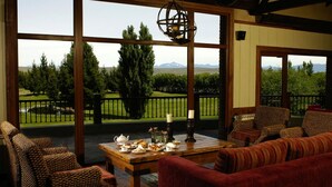 A cozy seating area with a table set for tea, overlooking a well-maintained garden and distant mountains. - Hotel Posada Los Alamos (El Calafate)