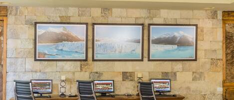 A reception desk with three monitors, black office chairs, and framed pictures of glaciers on the wall.