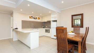A modern kitchen with white cabinetry, a central island, and a dining area with wooden chairs and a table.