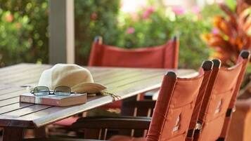 Une table en bois sur laquelle sont posés un chapeau blanc et des lunettes, entourée de chaises rouges.