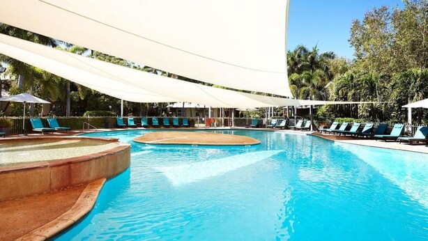 Una piscina con sillas de descanso y sombrillas.