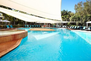 Una piscina con sillas de descanso y sombrillas.