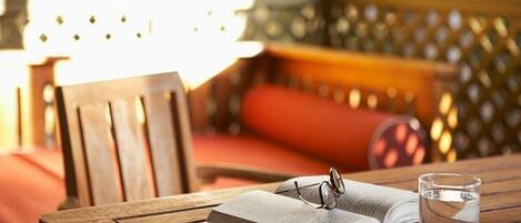 A wooden table with an open book, a pair of glasses, and a glass of water.