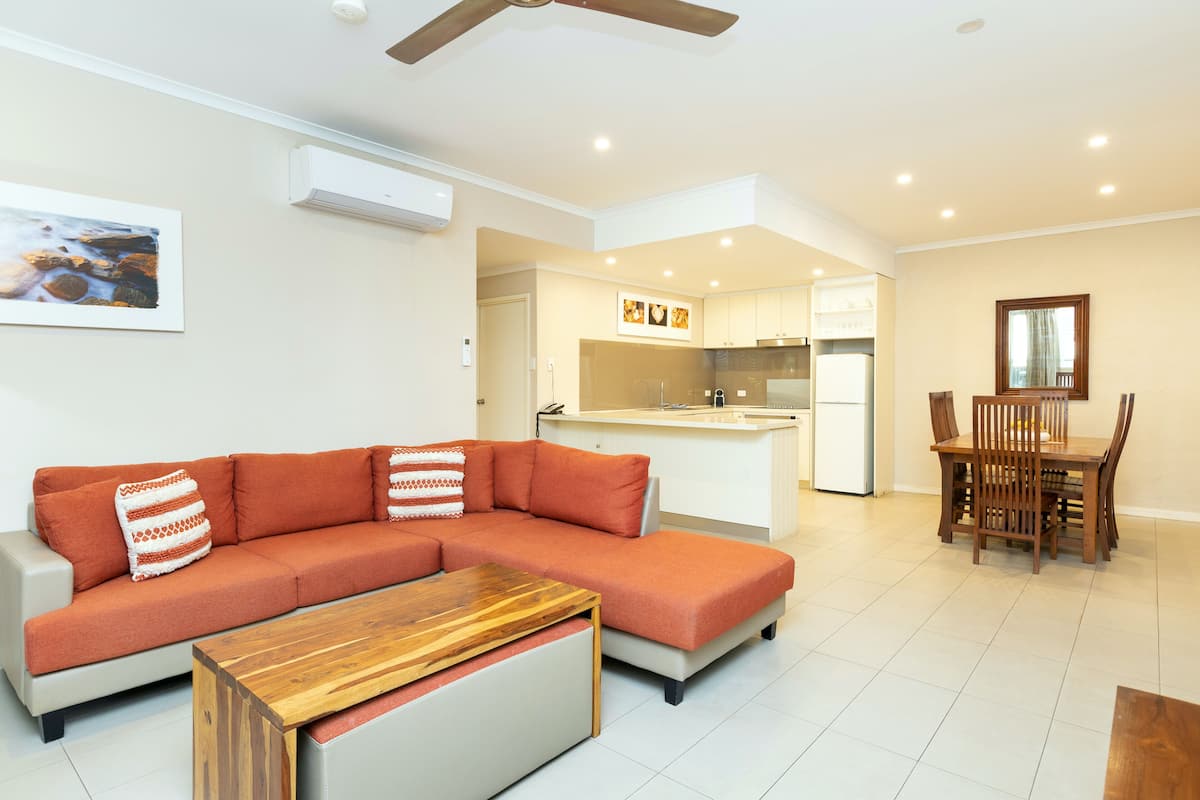 Uma sala de estar moderna com sofá seccional, mesa de centro de madeira e área de jantar com mesa e cadeiras de madeira.