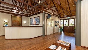 Un hall espacioso con suelos de madera, una recepción y un cuadro grande.