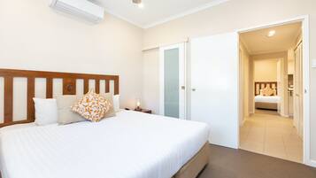 A hotel room with a large bed, a bedside table with a lamp, a wardrobe, and a door leading to a bathroom.