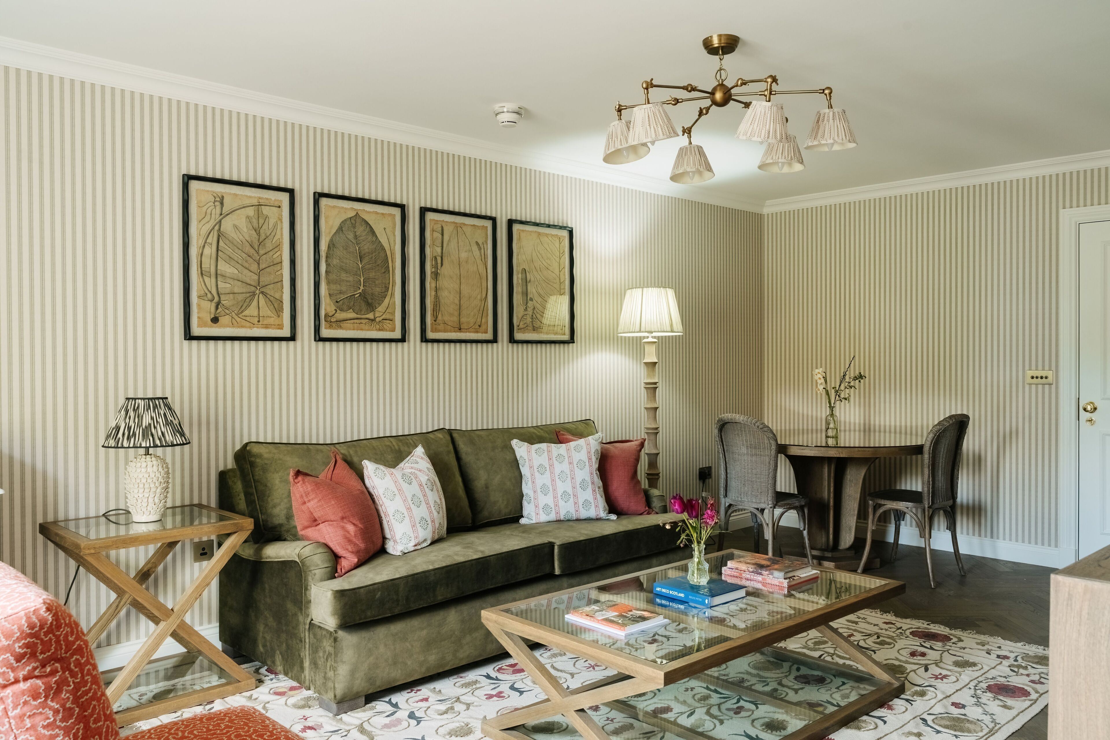 A living room with a sofa, a coffee table, a lamp, and framed botanical prints on the wall.