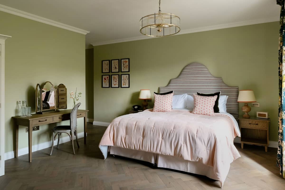 Un dormitorio con cama, mesitas de noche, un escritorio y una silla.
