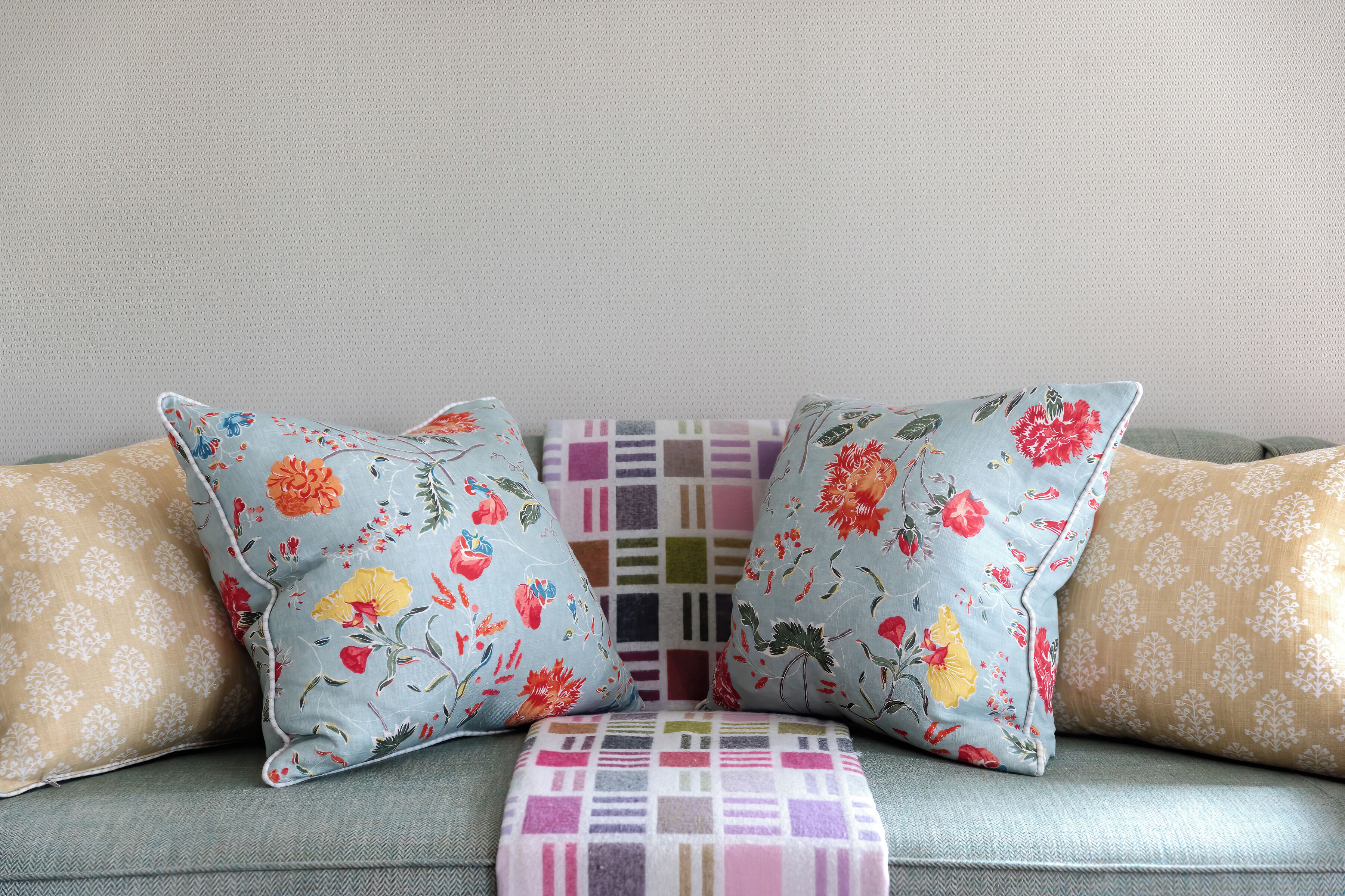 Un sofá con cojines de estampado floral y un cojín de patchwork.