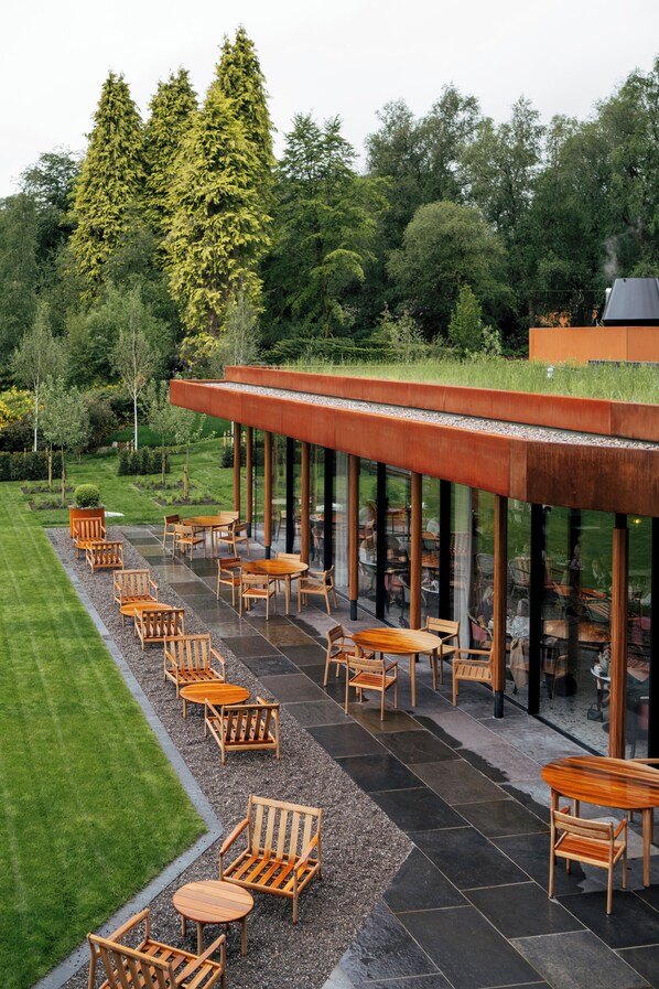 A modern outdoor seating area with wooden furniture and a glass enclosure. - Cromlix (Dunblane)