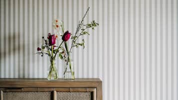 Una mesa de madera con un florero de flores sobre un fondo de papel tapiz a rayas.