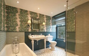 A bathroom with a bathtub, sink, toilet, and a glass-enclosed shower.