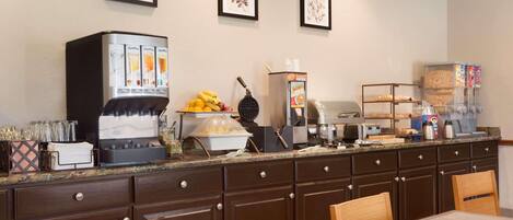 Una cocina con cafetera, frutero y dispensador de café.