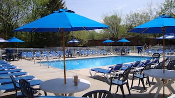 Relax by the pool surrounded by lounge chairs and tables, shaded by umbrellas.