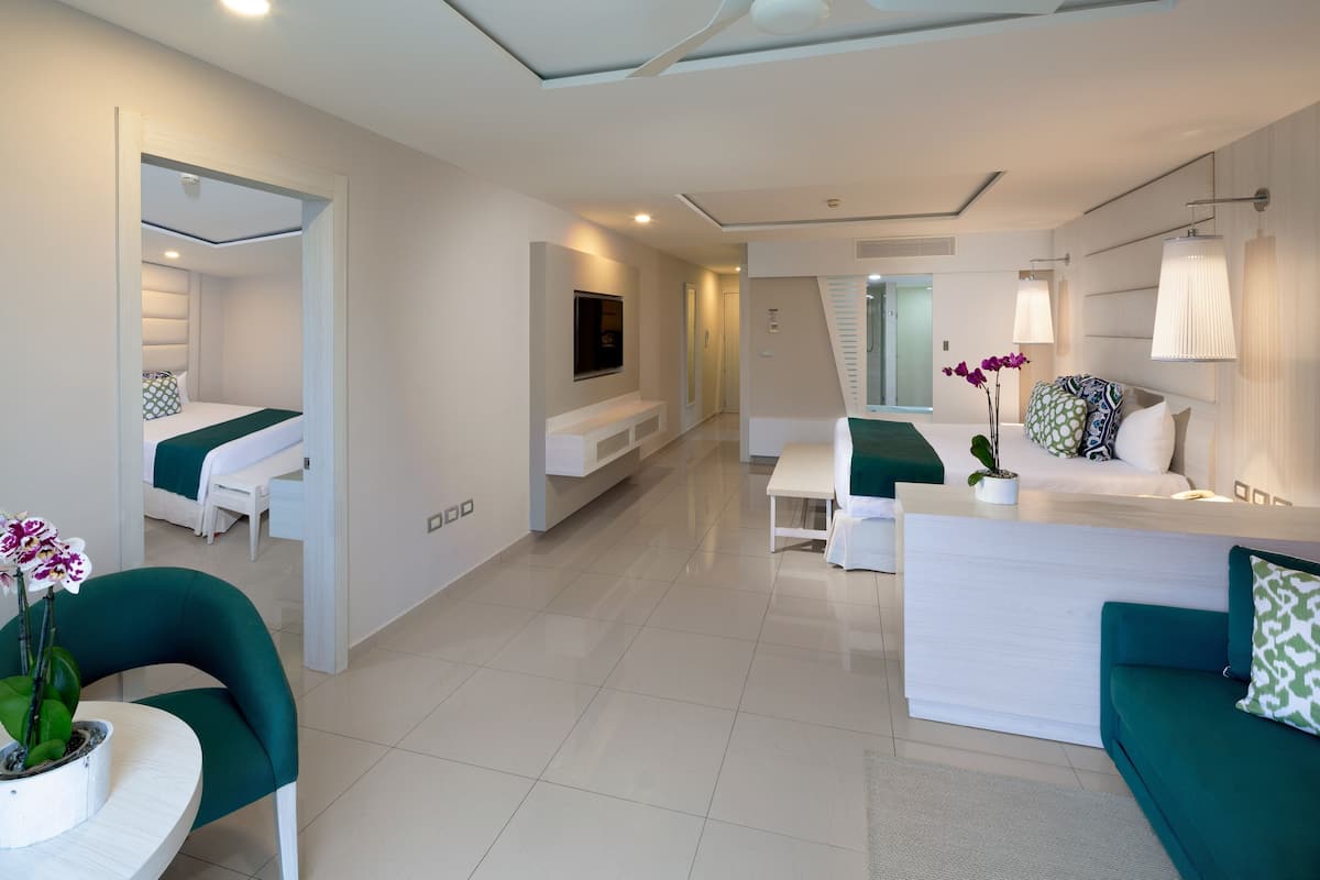A modern hotel room with a bed, a desk, a sofa, and a TV.