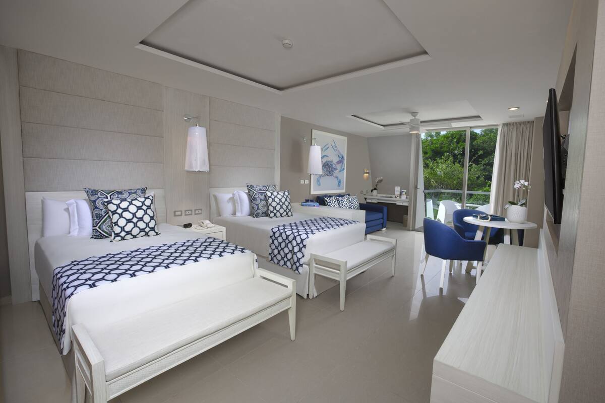 A hotel room with two beds, a desk, and a chair.