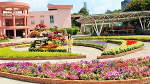Un bâtiment à la façade rose et doté d’une galerie couverte agrémentée de fleurs colorées.