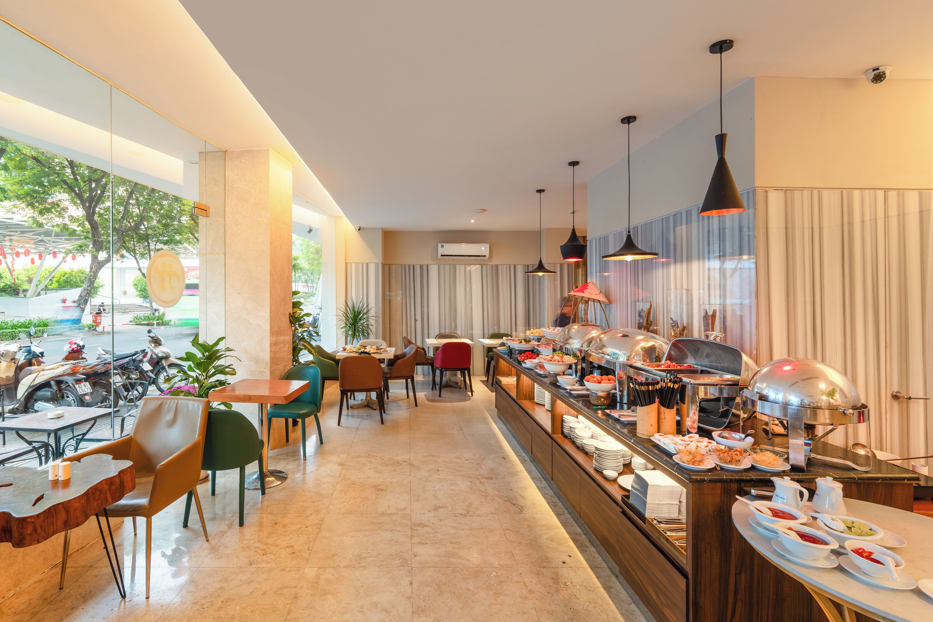 A modern hotel lobby with a buffet, seating area, and large windows.