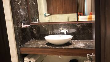 A modern bathroom with a marble vanity, a large mirror, and a sink.