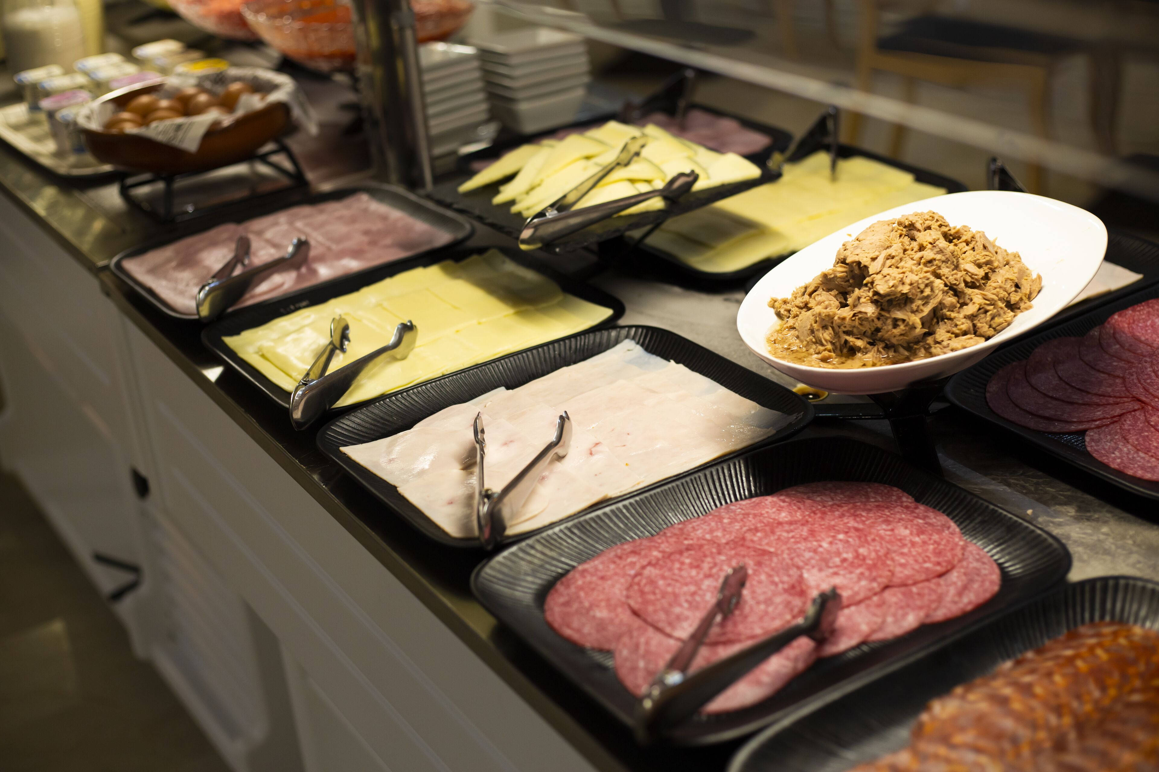 Un bufé con diversas opciones de comida, incluyendo carnes y quesos.