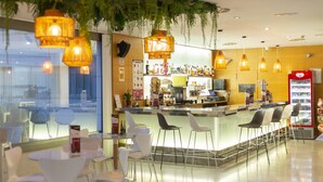 Un espace bar moderne avec des luminaires suspendus, un comptoir et des tabourets de bar.