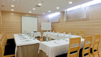 A conference room with tables set for a meeting, equipped with microphones, water bottles, and glassware.