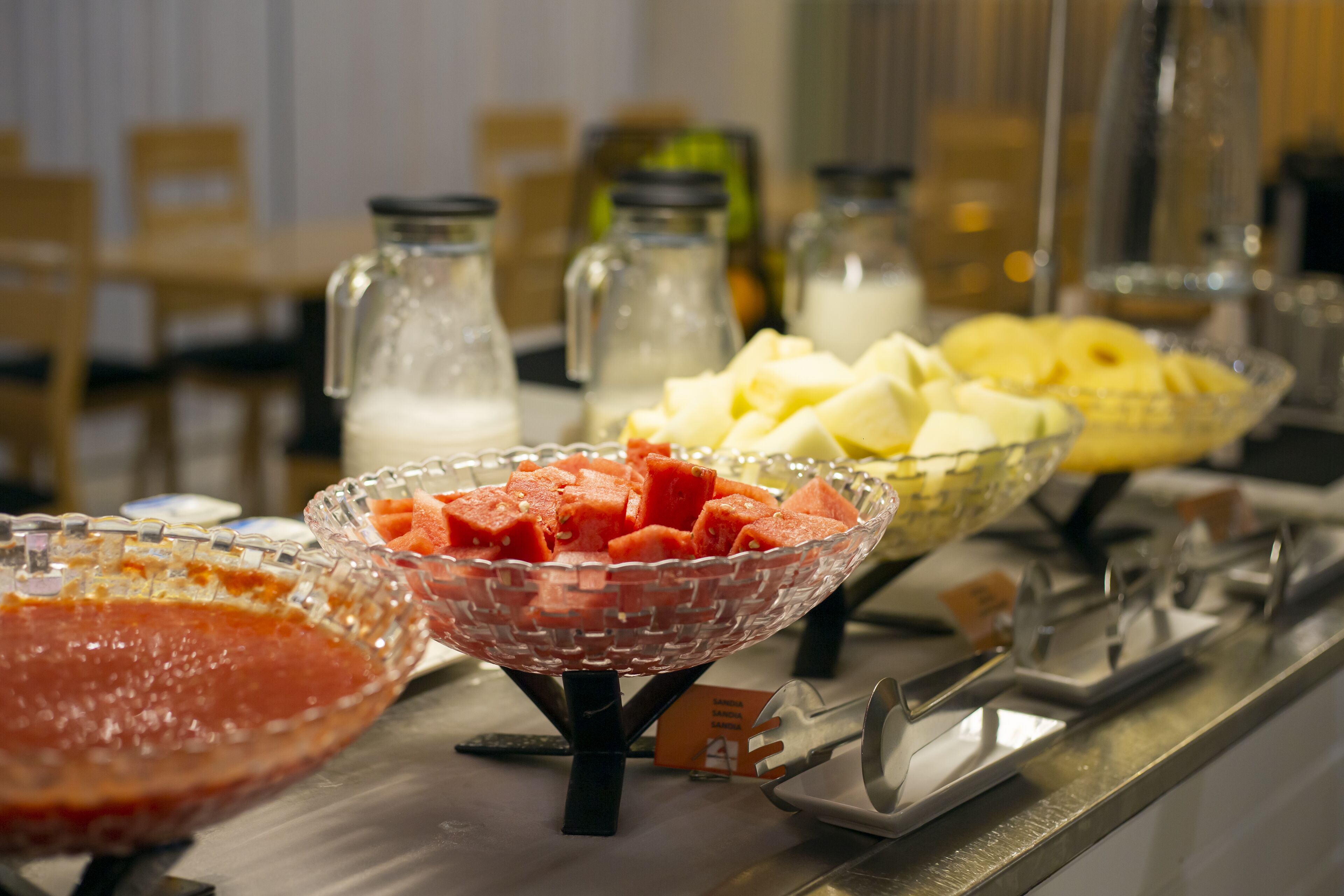 Un bufé con diversas opciones de comida, incluyendo sandía, queso y otros platos.
