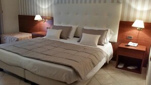 A hotel room with a large bed, two bedside tables, and a nightstand with a lamp. - Hotel Leonessa (Volla)