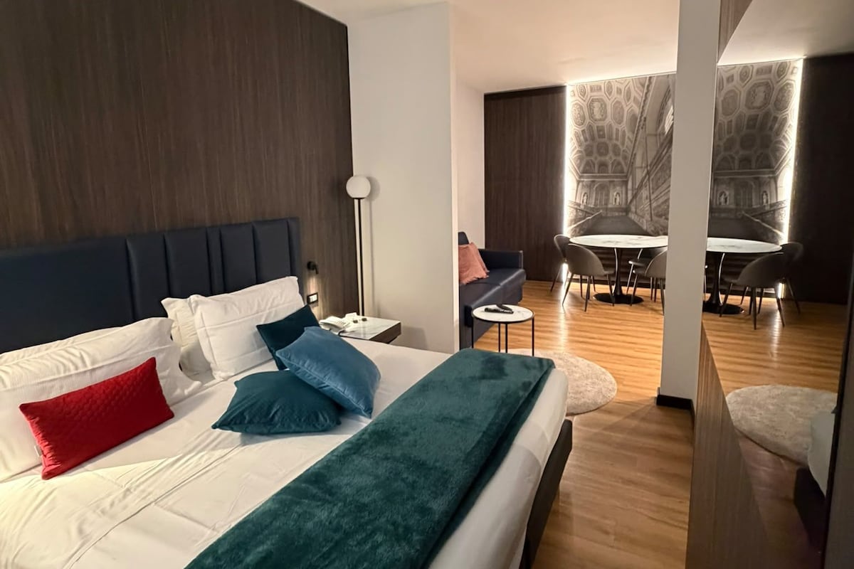 Et moderne hotelværelse med en stor seng, et skrivebord og et spiseområde.