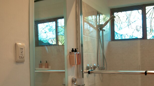 A modern bathroom with a glass sink, a glass shower enclosure, and a large mirror. - The Country Guesthouse (Stellenbosch)