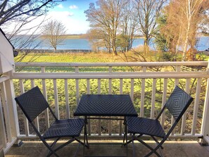 A balcony with a table and two chairs, overlooking a body of water and a grassy field. - Normanton Park Hotel, BW Signature Collection (Oakham)