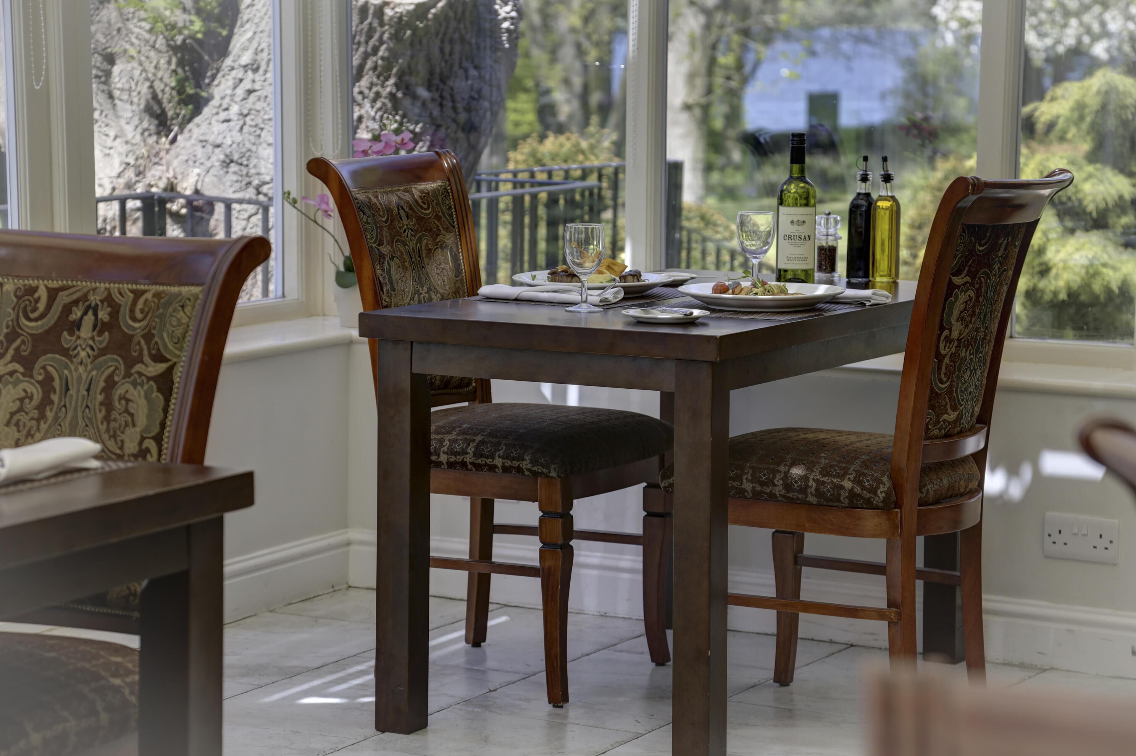 Una mesa de comedor con sillas, una botella de vino y una copa.