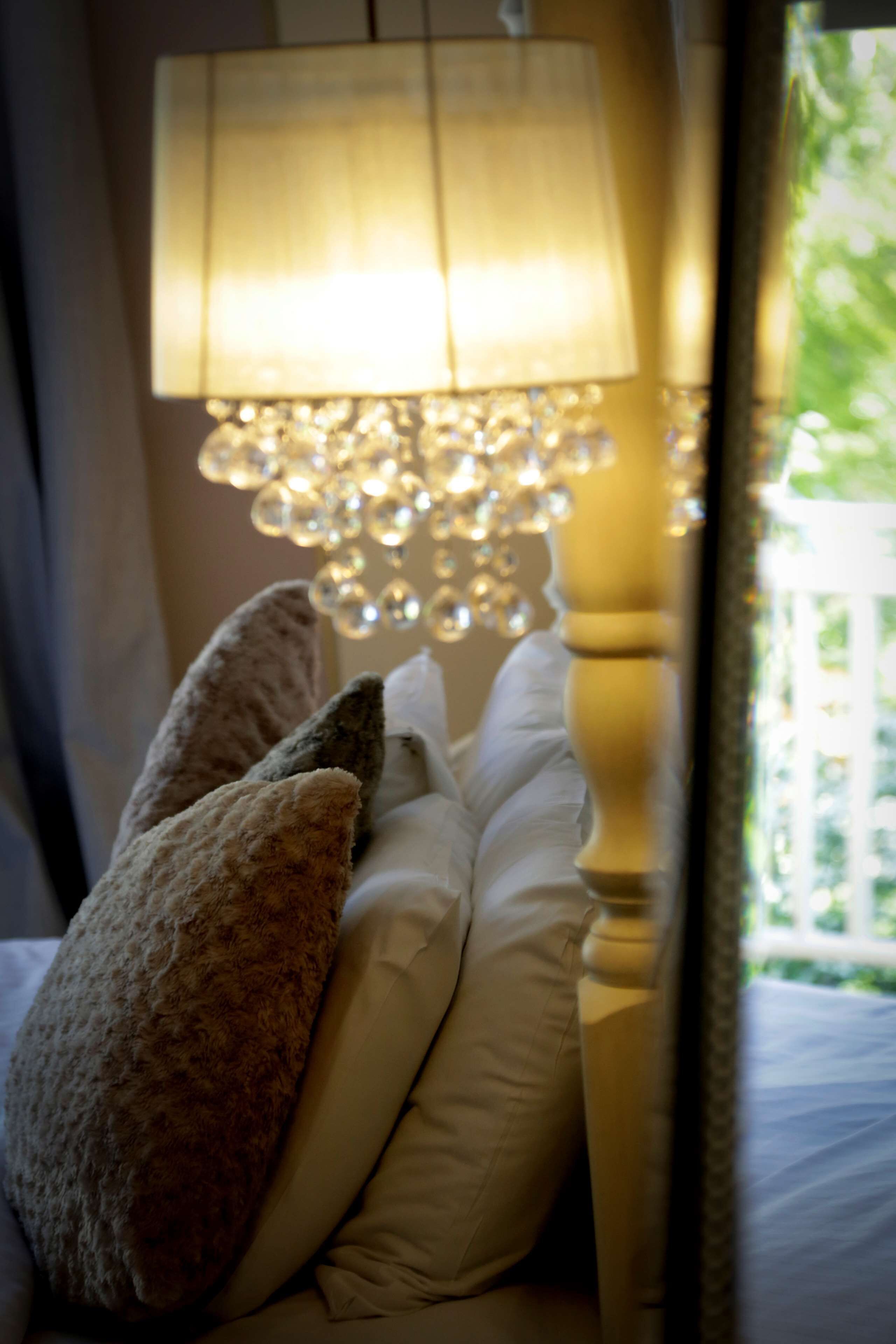 Un lit avec deux oreillers et une lampe dotée d’un abat-jour décoratif.