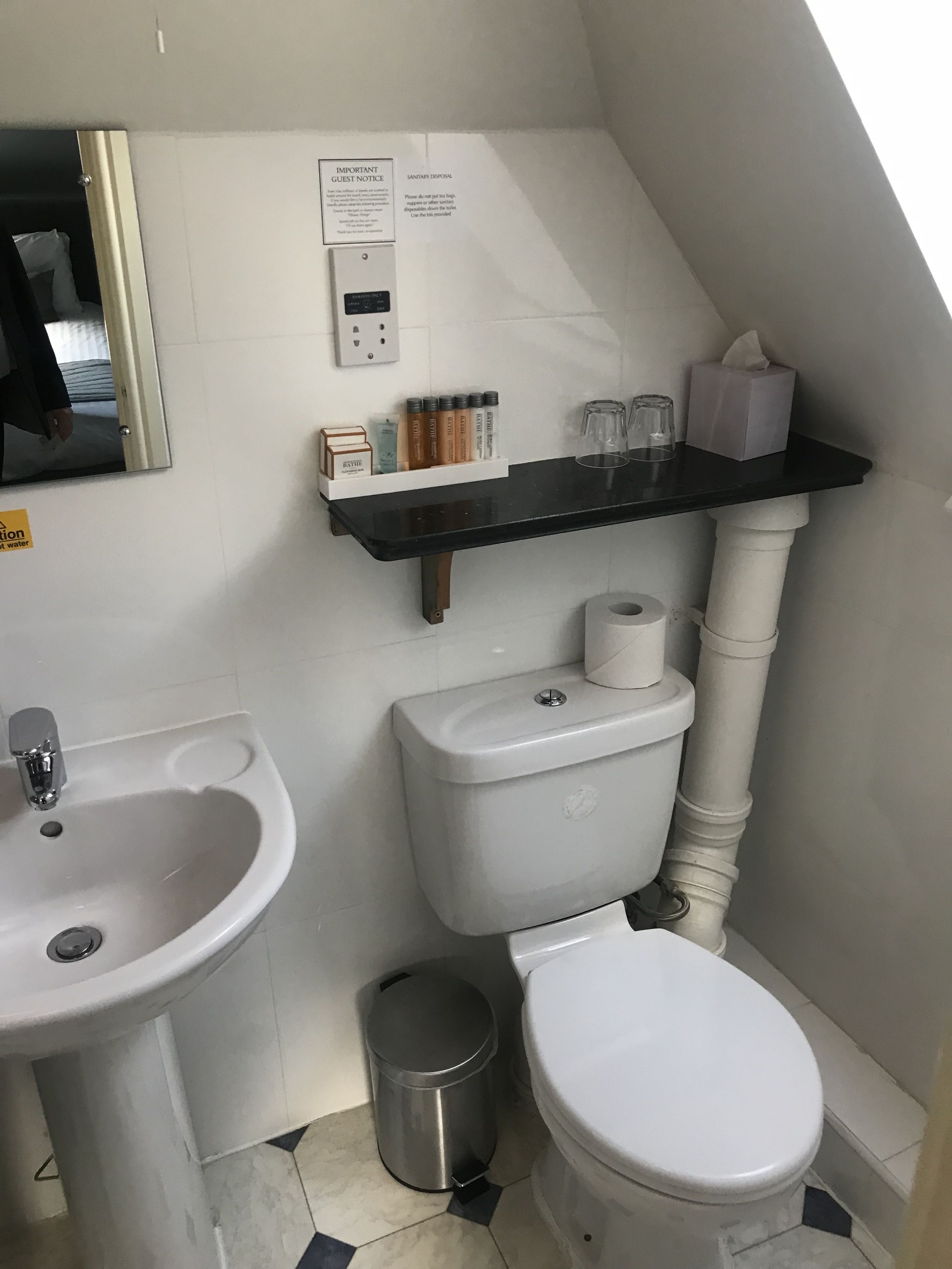 A small bathroom with a sink, toilet, and a shelf with toiletries.