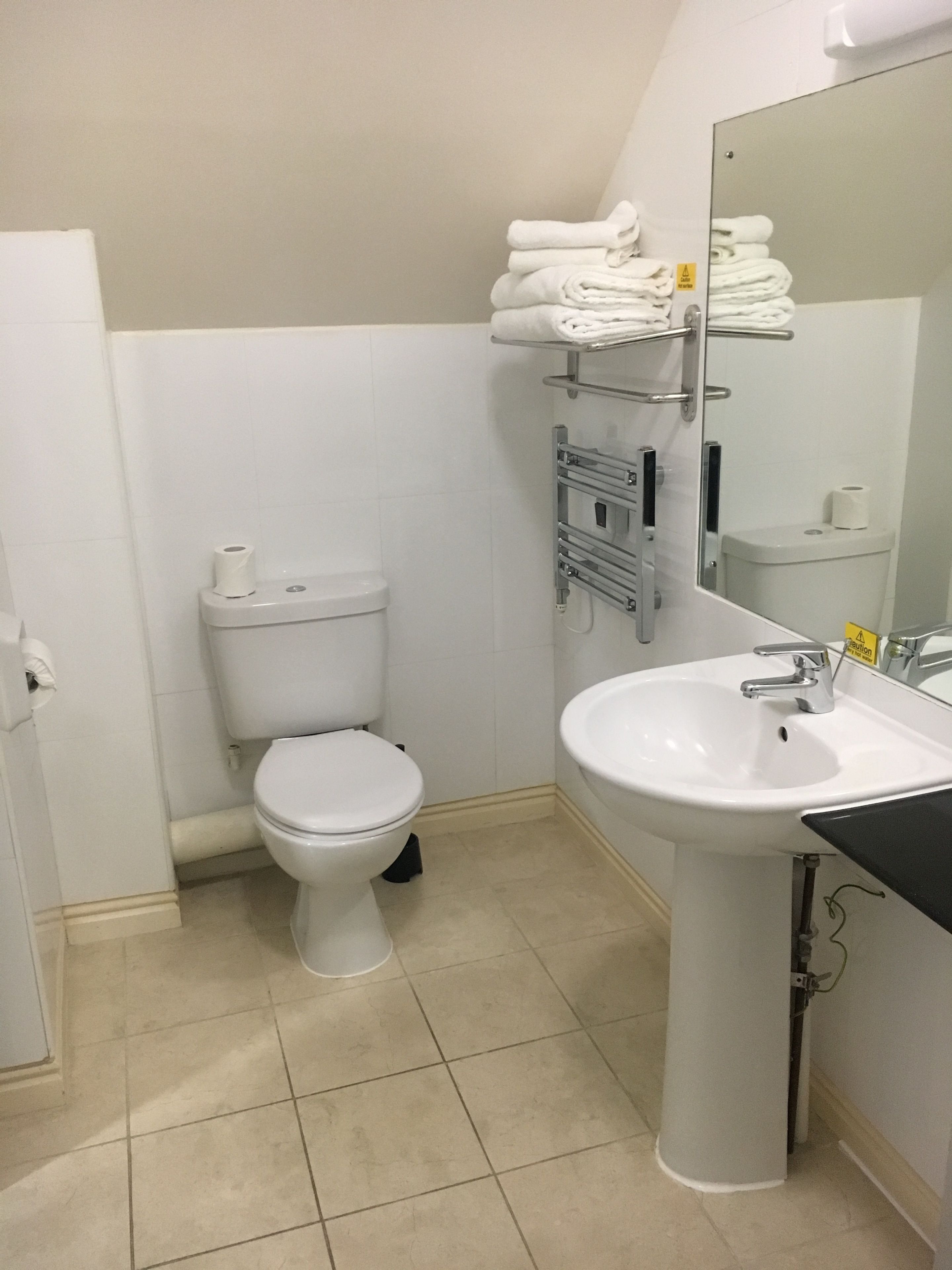 A bathroom with a toilet, sink, and towel rack.