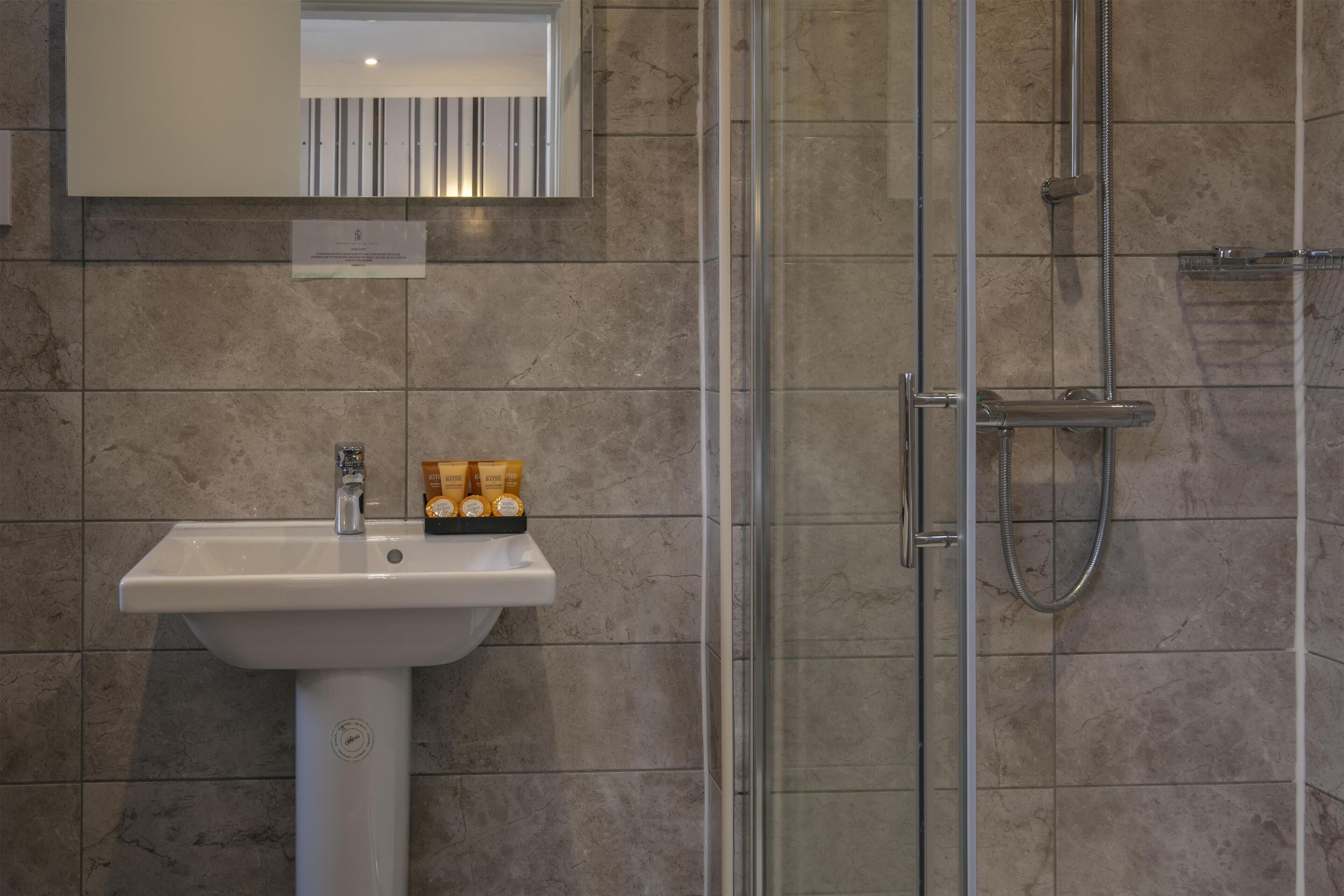 Un baño con lavamanos, espejo y ducha.