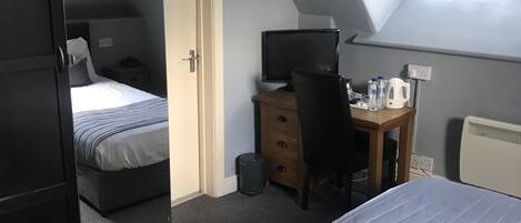 Un dormitorio con dos camas, un escritorio, una silla y un radiador.